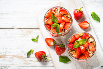 Greek yogurt with fresh strawberry and granola. Top view with copy space at white table.