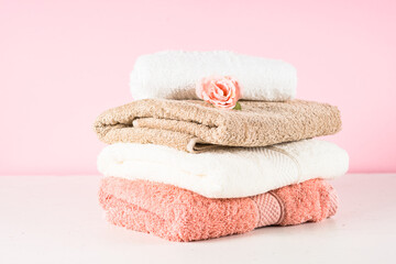 Obraz na płótnie Canvas Bath towel stack at bathroom. White pink and beige towels at pink background.