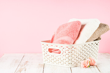 Bath towels in the basket at bathroom. White pink and beige towels.