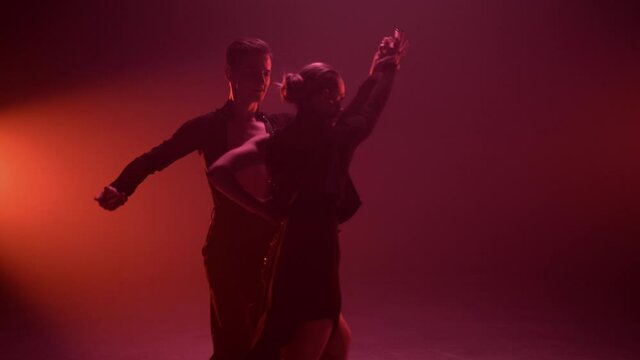 Graceful man woman dancing indoors. Sexy couple performing paso doble on stage.