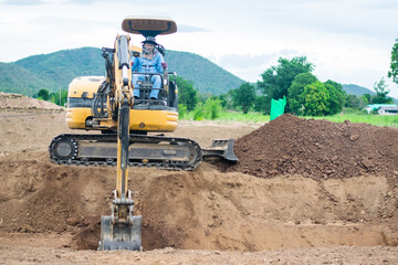 mini excavator digging soil with mountain background