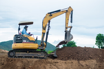 mini excavator digging soil with mountain background