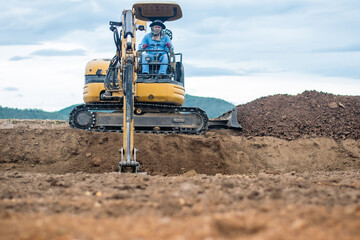 mini excavator digging soil with mountain background