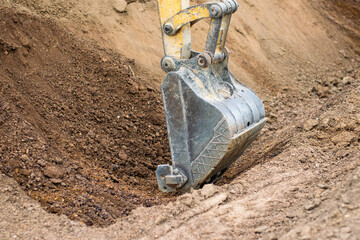 A mini excavator is digging the soil in the field.