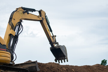 A mini excavator is digging the soil in the field.