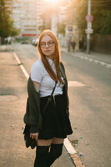 Fototapeta premium beautiful red-haired woman in a green sweater in the city at sunset.