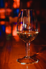 Wineglass on a blurred background. Glass in the twilight. Colored highlights on a glass. Bokeh.