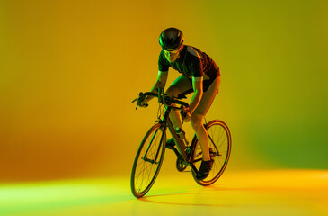Fototapeta na wymiar Cyclist riding a bicycle isolated against neon background