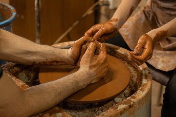 Training for work in the potter's wheel. A man and a woman work together with clay.