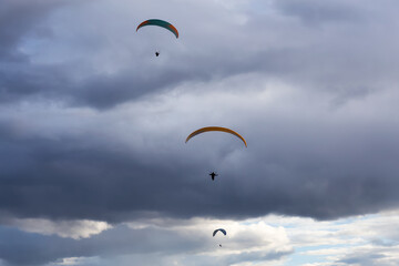 Adventurous People Flying on a Paraglider around the mountains. Savona, British Columbia, Canada.