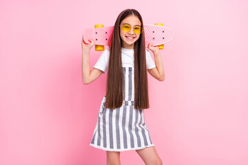 Photo of charming happy pretty little girl hold hands skateboard smile weekend isolated on pink color background