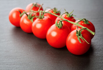 twig of cherry tomatoes on gray slate background