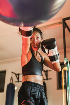 Thai female Muay Thai athlete with a punching bag