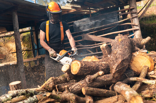 Man cutting wood with chainsaw at sawmill 