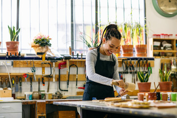 Positive female artisan restoring wooden piece 