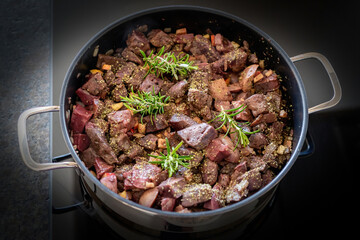 fresh liver, heart and kidneys from a red deer yearling sliced in a cooking pot, with rosemary, onions, apple, salt and pepper