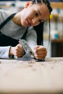 Skilled female woodworker working with jointer 