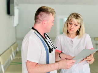 Two doctors a man and a woman are examining medical documents.