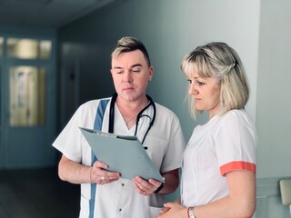 Two doctors a man and a woman are examining medical documents.