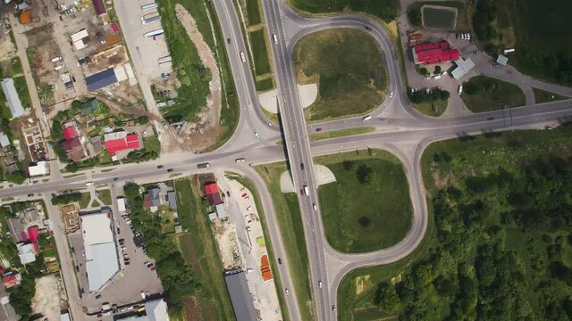 Aerial drone view of highway multi-level junction road with moving cars near to city haos. camera rotates. The concept of the urban city. Ukraine Vynnyky