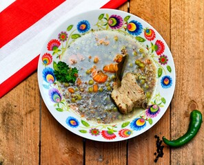 Green soup with buckwheat, carrot, chilli papper pork meat and green bean in white plate on wooden background..