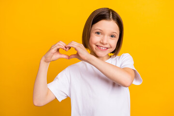 Photo portrait little girl bob hairdress showing heart with hands isolated vibrant yellow color background