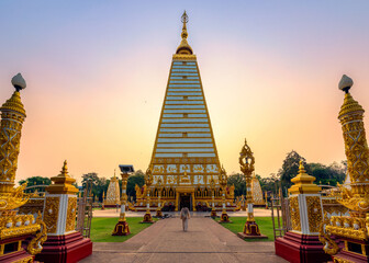 Asian woman walking in golden stupa Sri Maha Pho Chedi with colorful evening sky at Wat Phra That...