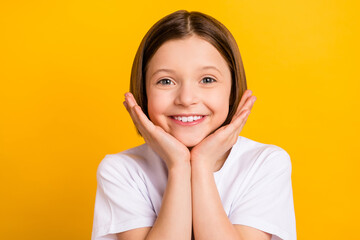 Photo portrait little girl bob hairdress keeping hands near face smiling nice overjoyed isolated bright yellow color background