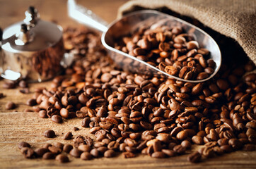 heap of roasted coffee beans with metal scoop on wooden table