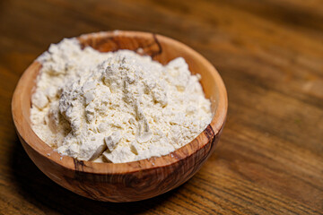 flour in a wooden dish on the kitchen table. 