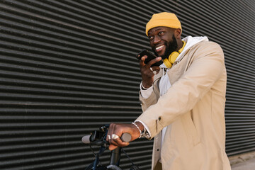 Man sending a voice message with a mobile standing on an electronic scooter.