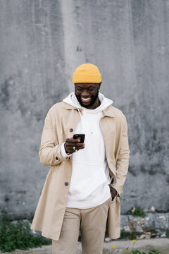 Afro Man Smiling While Texting With A Mobile