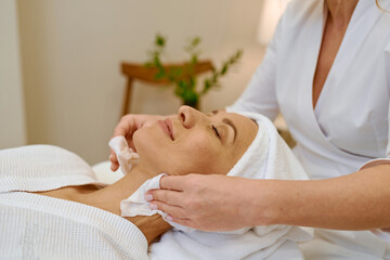 Cosmetologist doing face massage adult woman patient in beauty salon