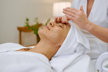 Cosmetologist doing face massage adult woman patient in beauty salon