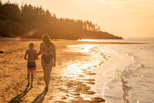 Mother and Son Walking  Along Red Sand Beach on PEI at Sunset