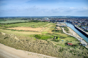 Fototapeta na wymiar The dunes on West Beach protecting the golf course and revealing the River Arun running past the town of Littlehampton. Aerial photo.