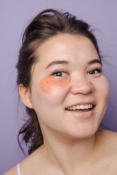 Young brunette east asian woman wearing  skincare eyepatches smiling