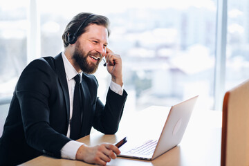 The technical support manager in the headset advises the customer. Sits in a modern office, communicates video communication.