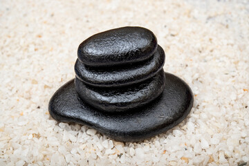 Massage black stones piled up on white pebble background