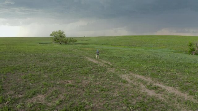 Senior, athletic, overweight male is running on a trail through green prairie, Pawnee National Grassland in Colorado, aerial view