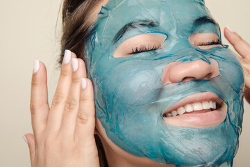 Young eastern asian woman with blue face sheet mask touching her face