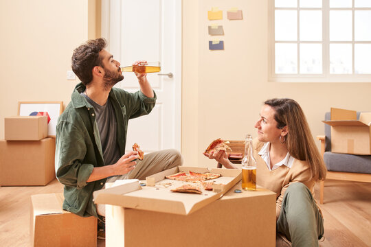 Young man and woman enjoying pizza and beer during relocation