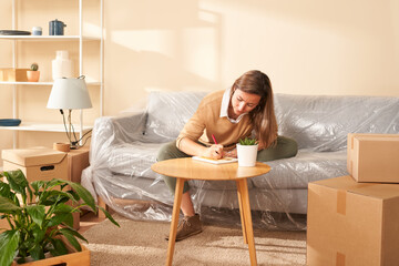 Young female writing in notepad during relocation