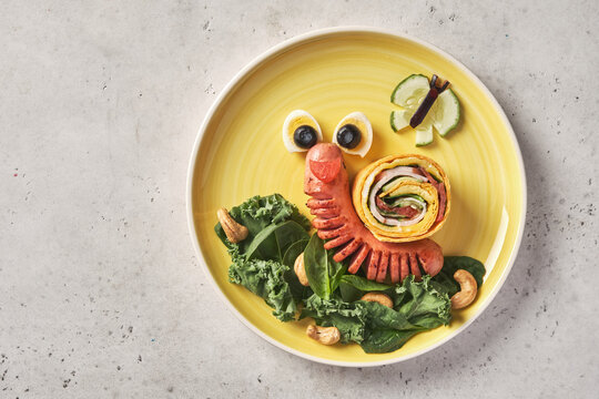 Naklejki Funny food idea for kids - Cute snail sausage and ham omelet tortilla wrap