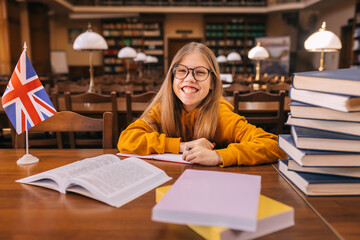 Laughing Smiling schoolgirl in a yellow sweater and glasses sitt