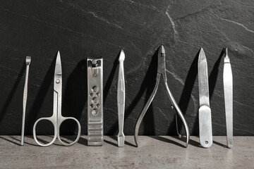 Set of manicure tools on grey table near black wall