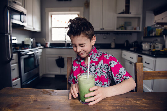 boy making a funny face after drinking a sour green smoothie