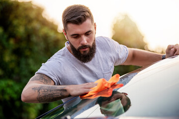 Young man cleaning his car with microfiber cloth