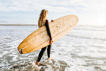 Female surfer walking at the beach with surfboard