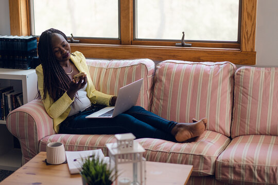 woman sitting on sofa working on computer. 